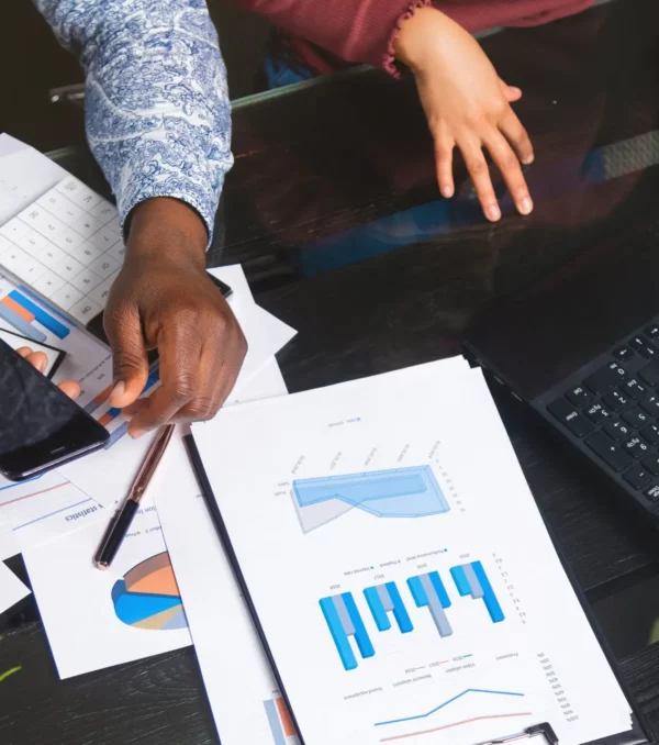 Part of hands of African-Americans in workflow with documents is top view. Various business colleagues sitting at table in modern office working with documents, calculators mobile phone. Can be used as business background